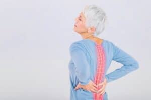 An illustrative image showing a person experiencing back pain in a typical scenario, such as while lifting heavy objects or sitting at a desk for prolonged periods.