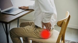Person sitting at a desk experiencing discomfort in the buttock and hip
